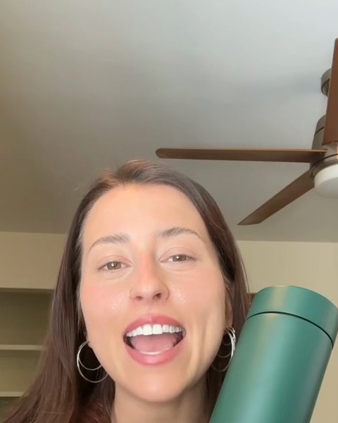 A woman holding a green Stop-Infusion Travel Mug