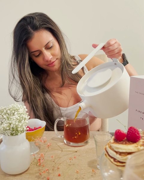 A woman pouring tea at a brunch table