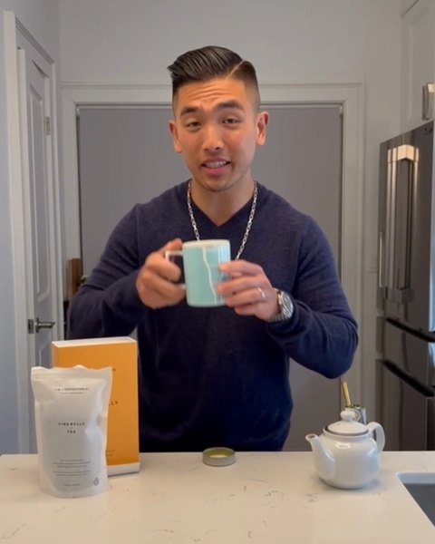 A man holding a mug of tea in his kitchen