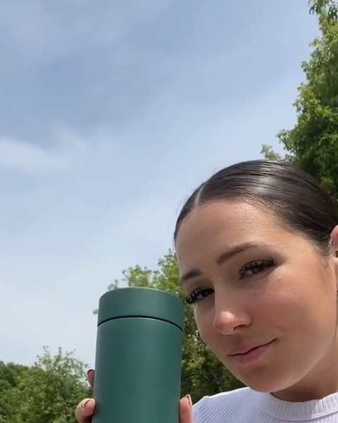 A woman outside with a green Firebelly travel mug